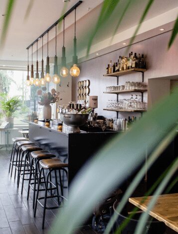 plano-interior-cafe-sillas-cerca-bar-mesas-madera 1